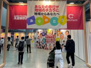 Eingang einer Messe des Portals Furusato Choice mit Bannern, Besucher gehen hinein