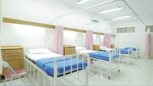 Leere Krankenhausbetten mit blauen Decken in einem hellen Mehrbettzimmer