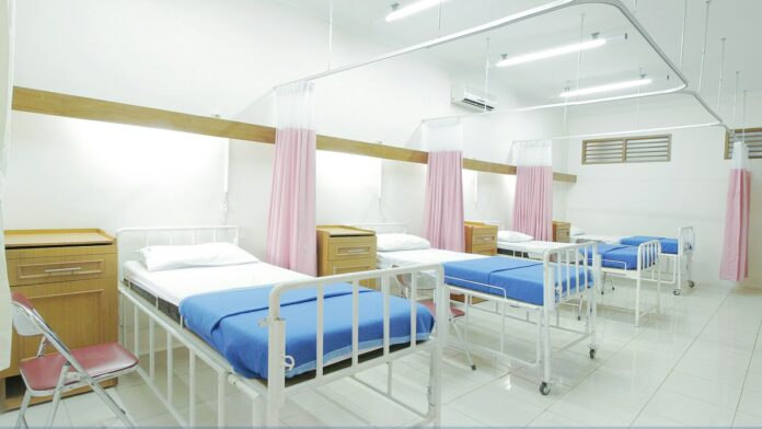 Leere Krankenhausbetten mit blauen Decken in einem hellen Mehrbettzimmer