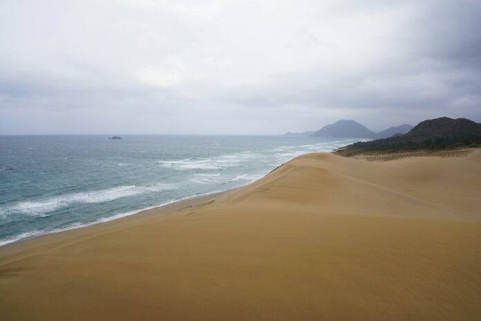 Die Sanddünen von Tottori am Meer unter bewölktem Himmel