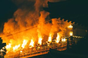 Fackeln an einem hölzernen Tempelgang bei einem Feuerfest in Nara (Symbolbild, nicht das Kebesu-Fest)