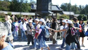 Eine große Gruppe japanischer Grundschüler mit Mützen bei einem Ausflug zum Tempel Tōdai-ji in Nara